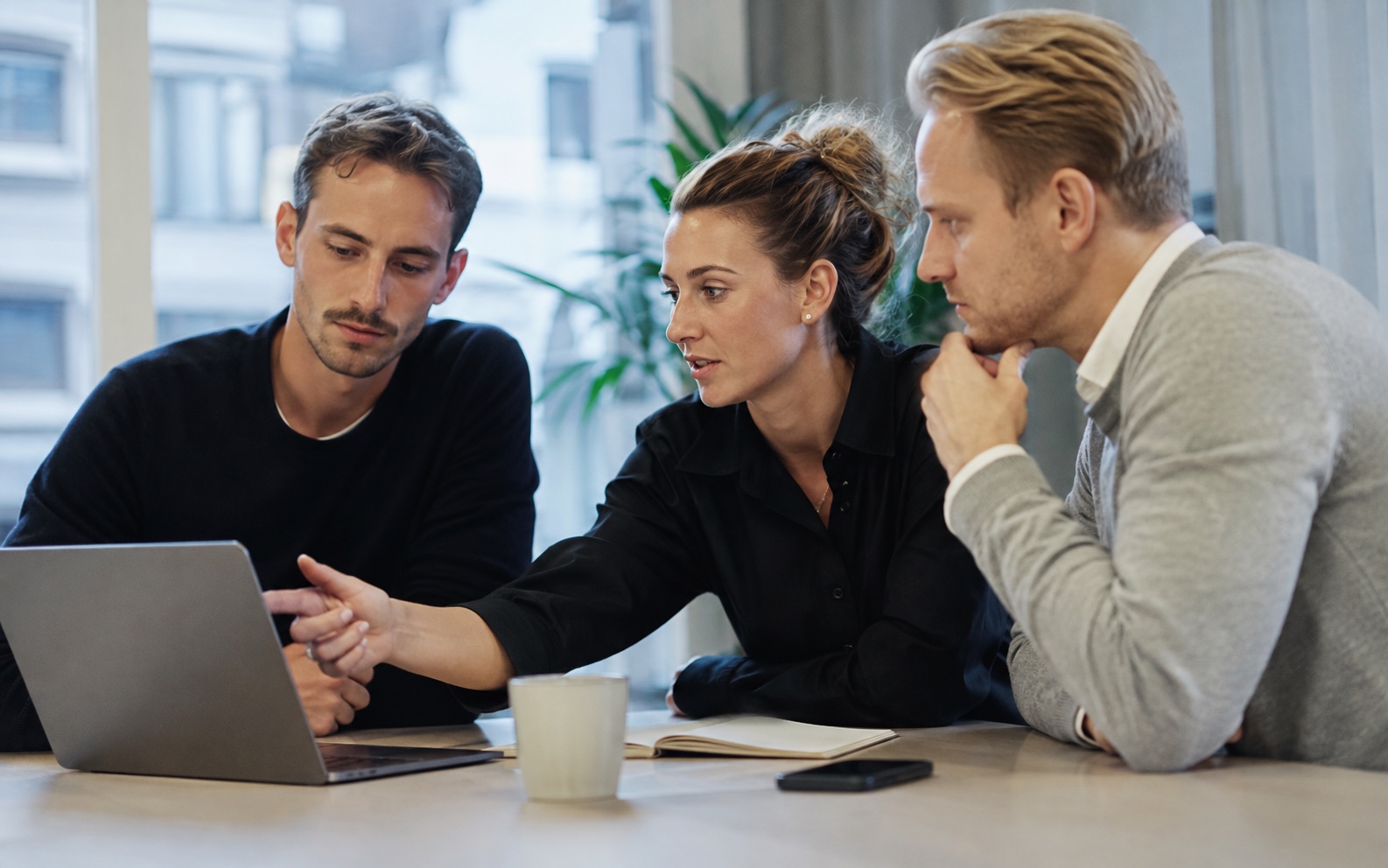 A founder-led team reviewing work together around a laptop